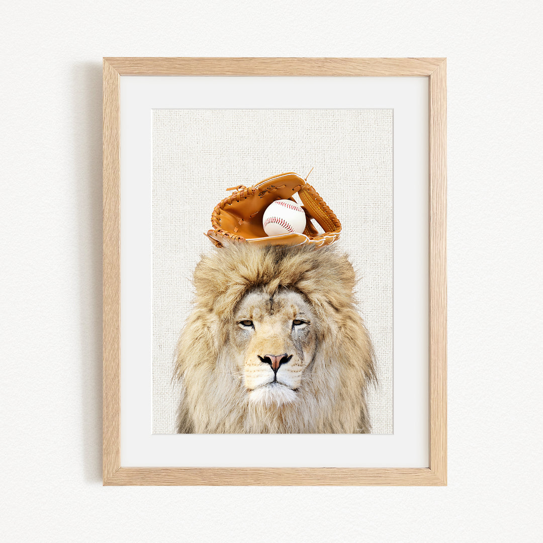 A framed image of a lion wearing a baseball glove on its head, with a baseball resting on top of the glove.
