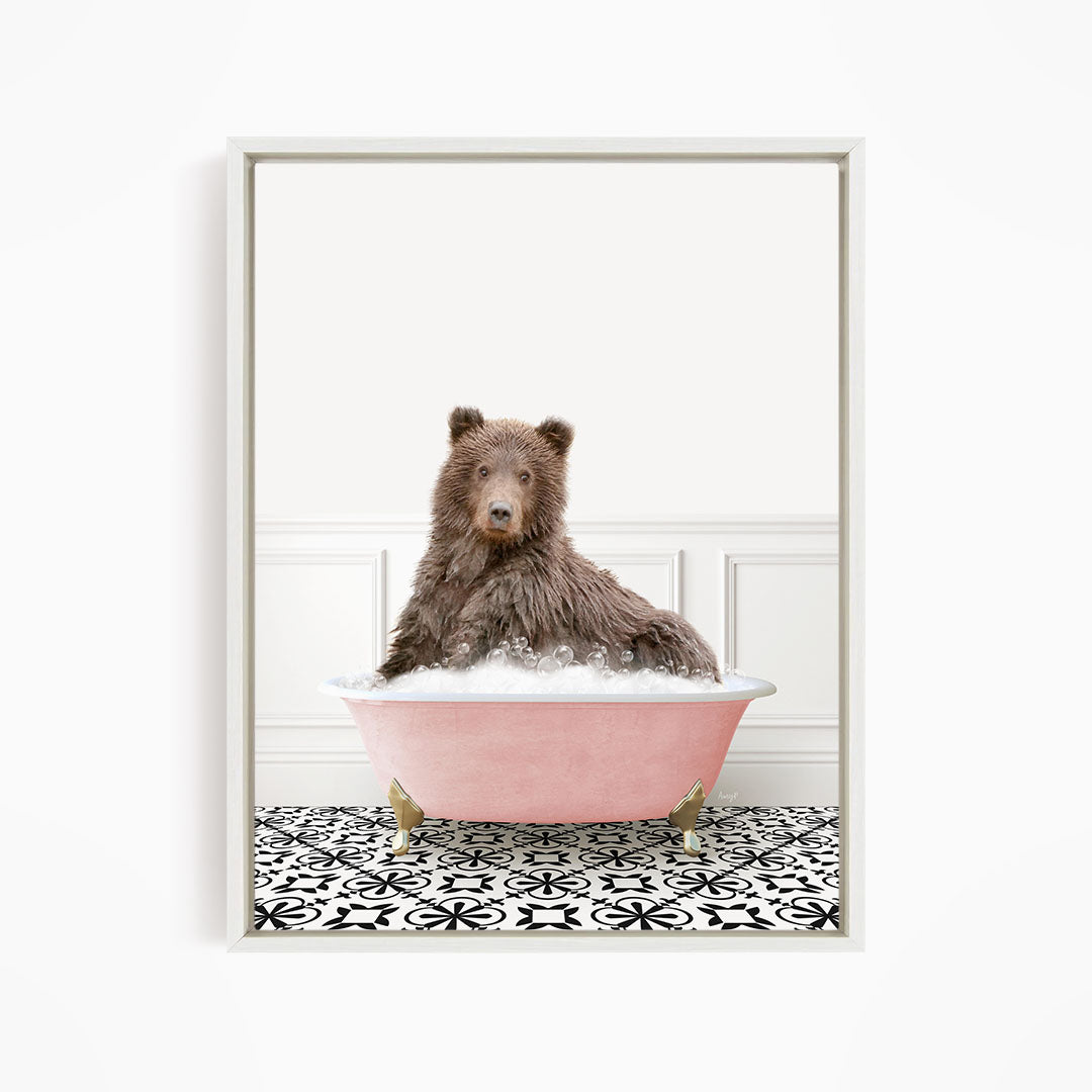 A brown bear sitting in a pink bathtub filled with bubbles, surrounded by a black and white patterned floor.