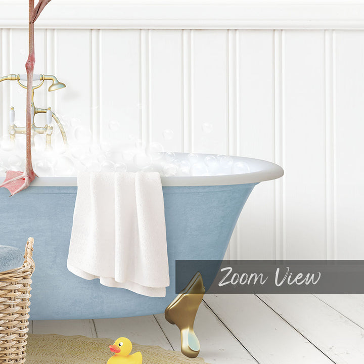 A blue claw-foot bathtub filled with bubbles, with a white towel hanging on the side and a rubber duck nearby.
