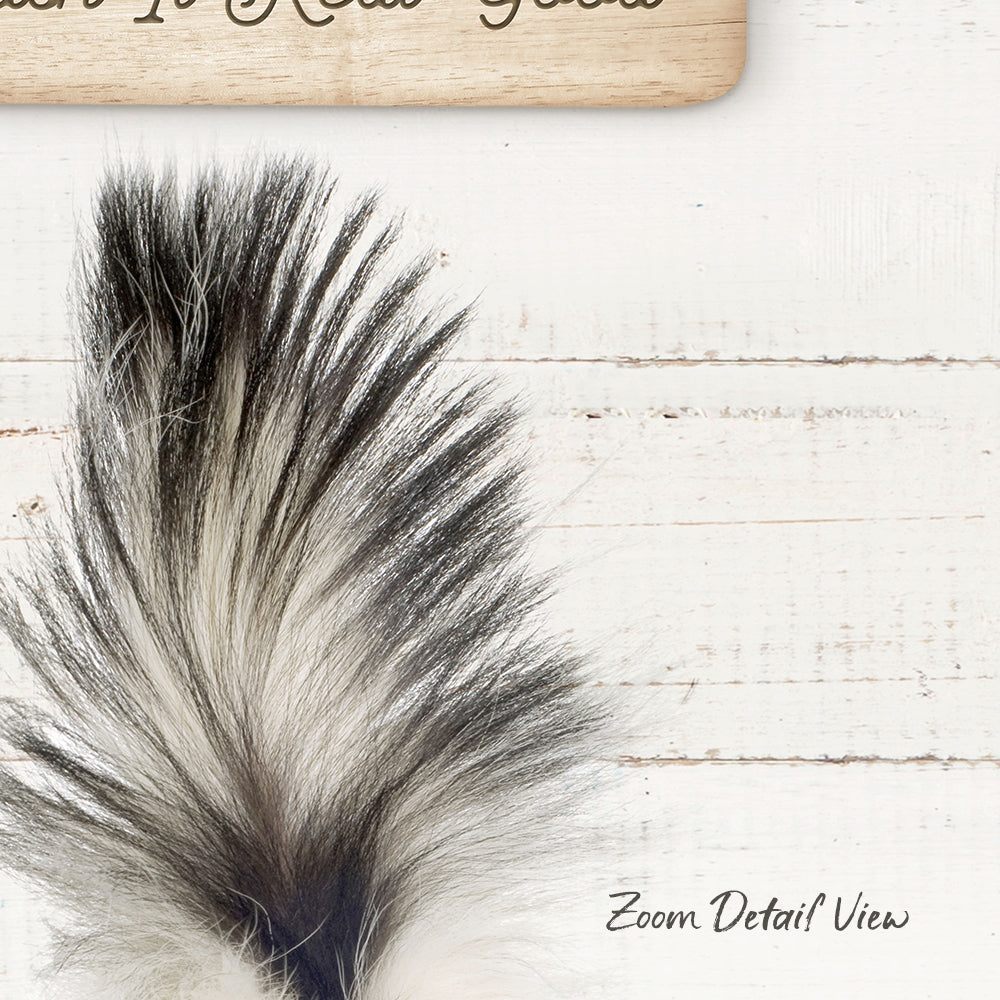 a close-up view of a fluffy, black and white feather against a white wooden background.