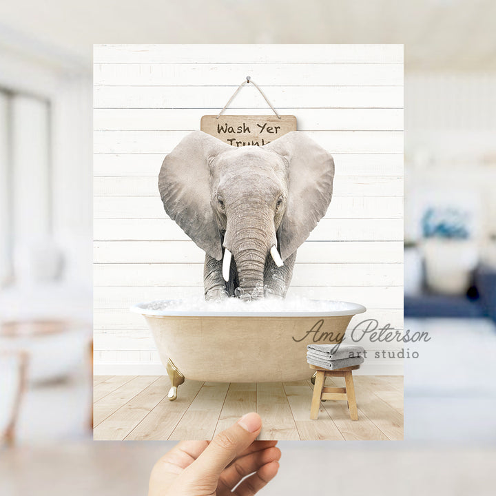 a person holding up a picture of an elephant in a bathtub