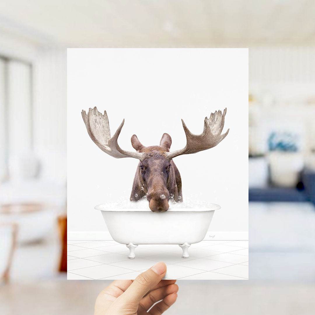 A moose with large antlers is sitting in a bathtub filled with water, creating a whimsical and humorous scene.