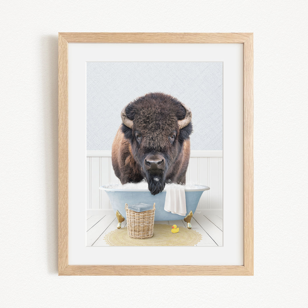 A buffalo standing in a bathtub filled with water, surrounded by a basket of toys and a yellow rubber ducky.