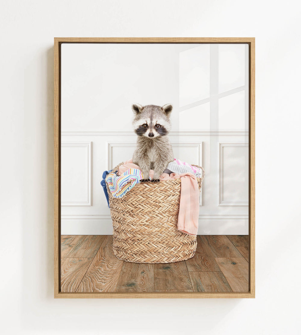 A raccoon sitting in a woven basket filled with clothes.