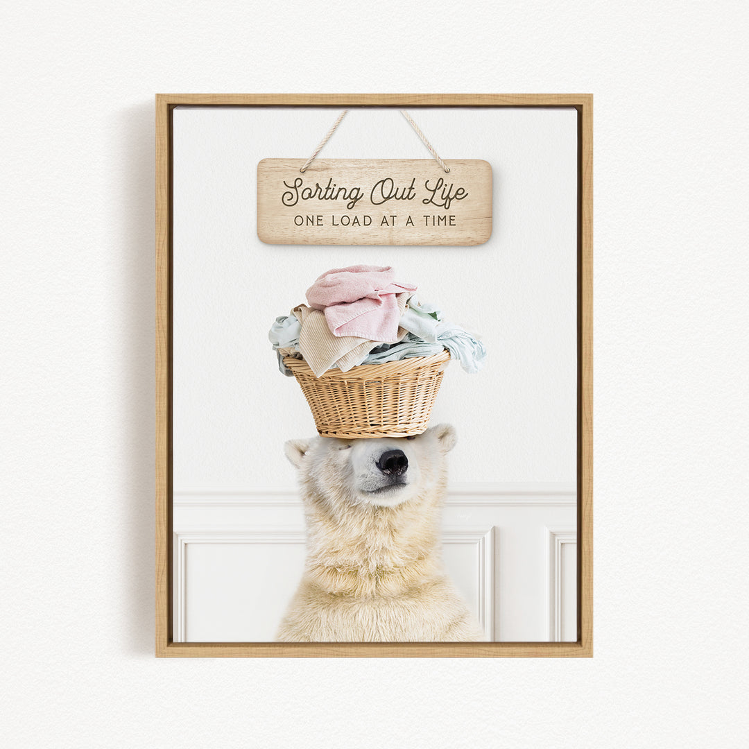A polar bear balancing a basket of laundry on its head, with a sign above that reads "Sorting Out Life One Load at a Time".