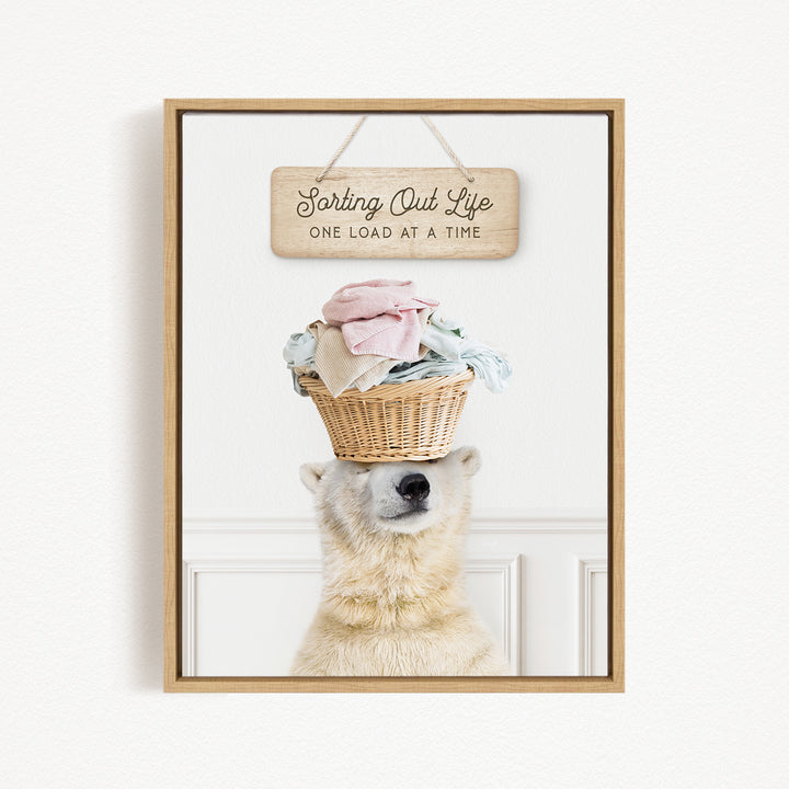 A polar bear balancing a basket of laundry on its head, with a sign above that reads "Sorting Out Life One Load at a Time".