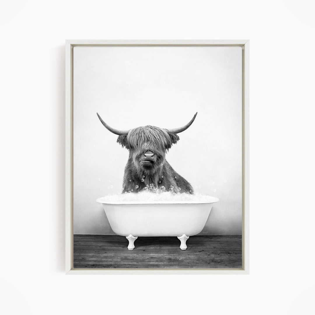 A black and white image of a Highland cow sitting in a bathtub filled with water.