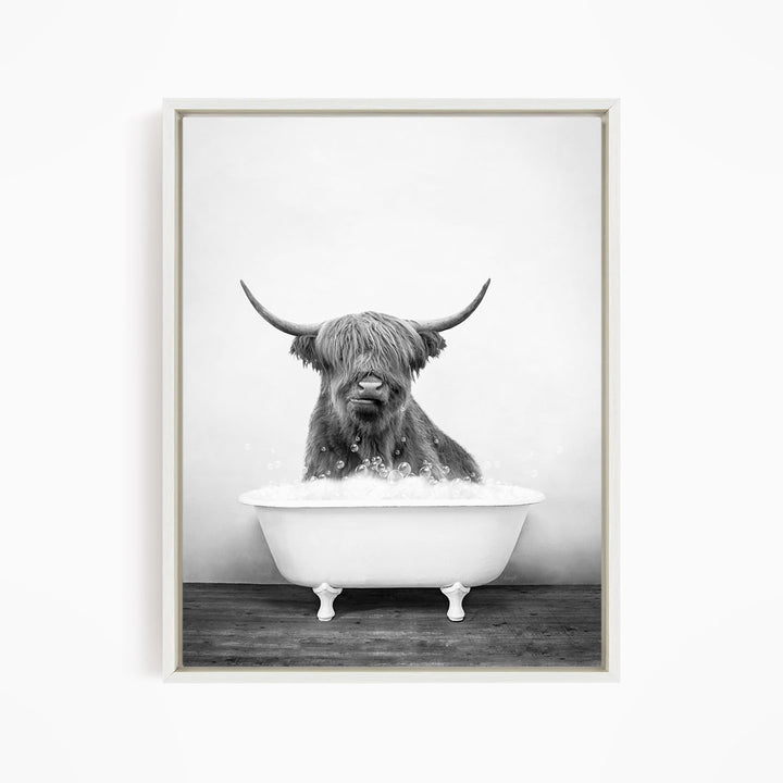 A black and white image of a Highland cow sitting in a bathtub filled with water.