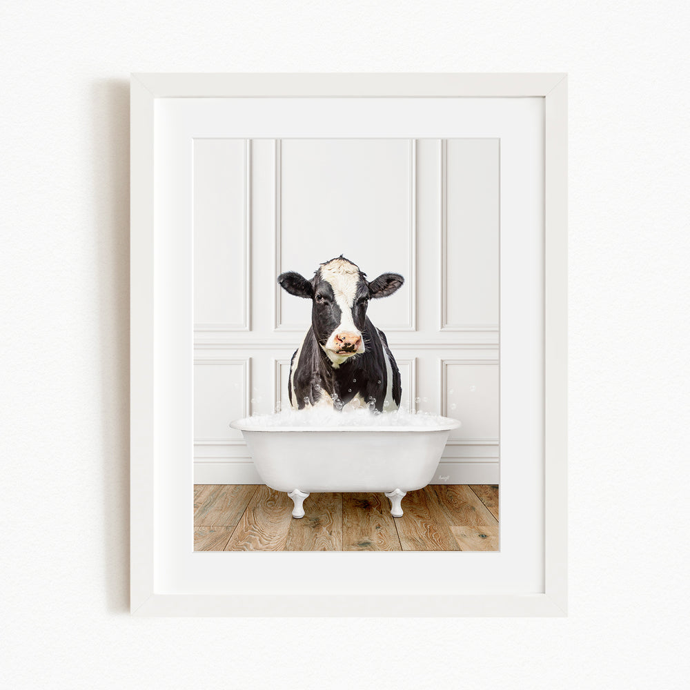 A black and white cow is sitting in a white bathtub filled with water, creating a whimsical and humorous scene.