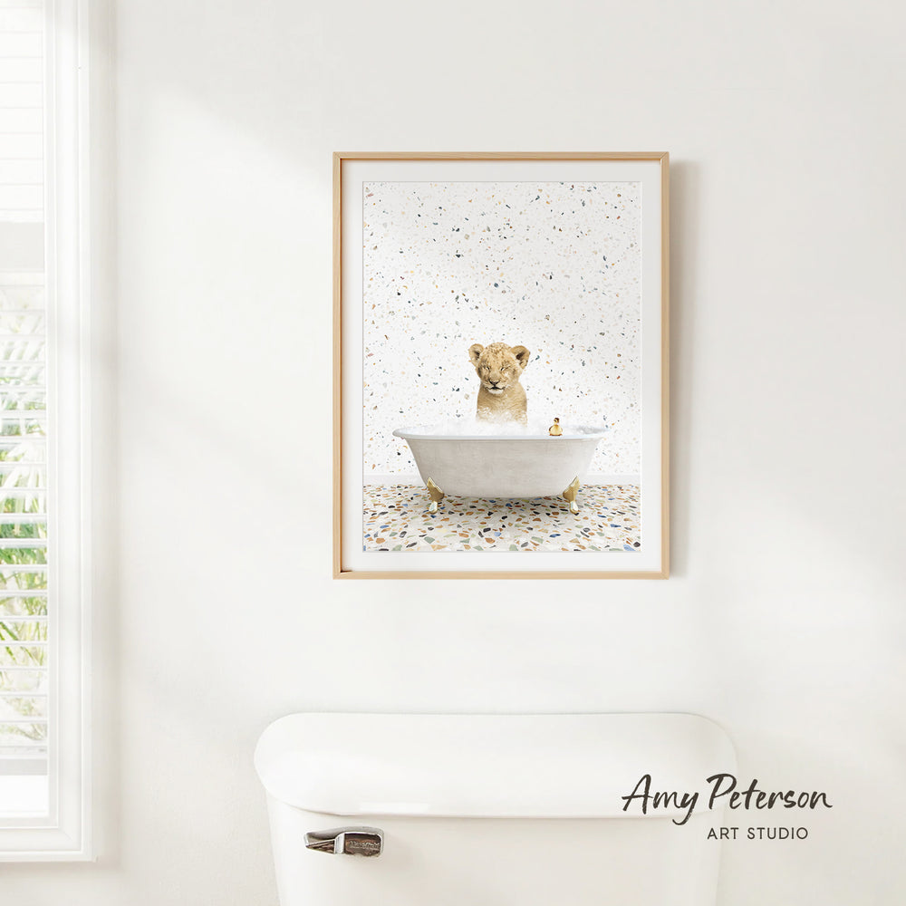 A framed print of a dog sitting in a bathtub is hanging on a white wall above a white toilet.