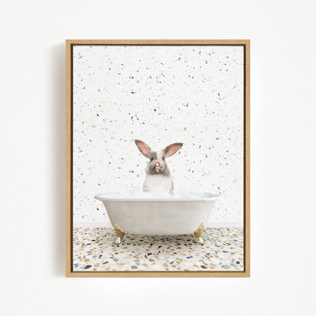 A white rabbit sitting in a white bathtub filled with water, surrounded by a speckled tiled floor.