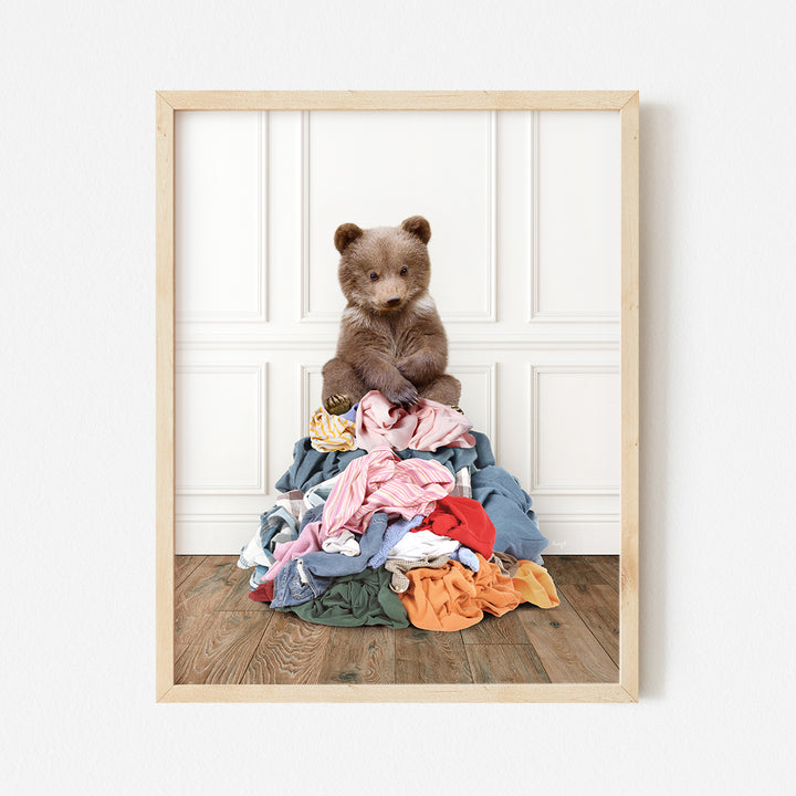 a brown teddy bear sitting on top of a pile of clothes