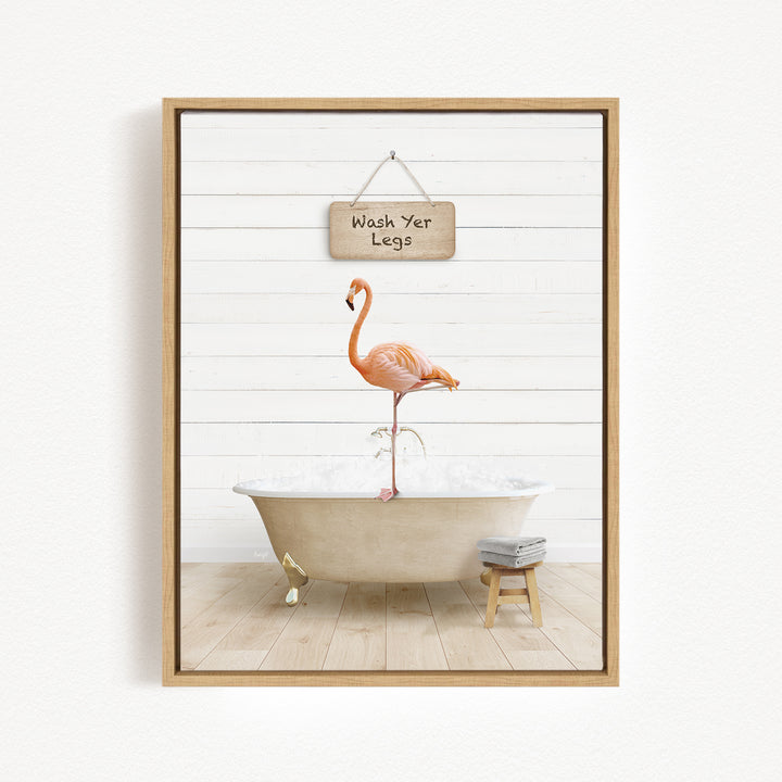 A framed image depicting a pink flamingo standing on a white bathtub, with a sign above it that says "Wash Yer Legs".
