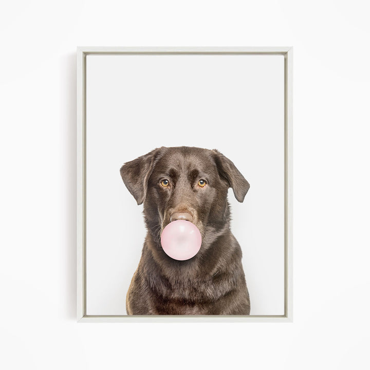 A brown dog is blowing a bubble with a pink bubble gum bubble.