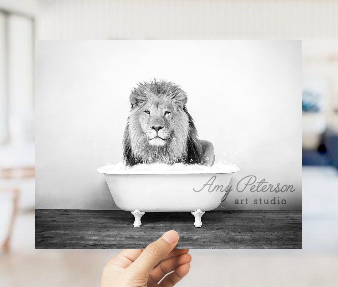 a hand holding up a black and white photo of a lion in a bathtub