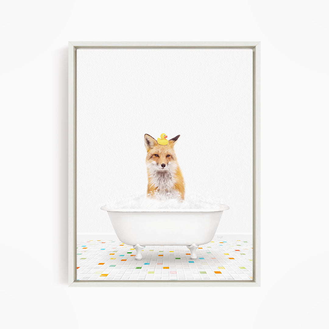 A fox is sitting in a white bathtub filled with bubbles, surrounded by a few rubber ducks.