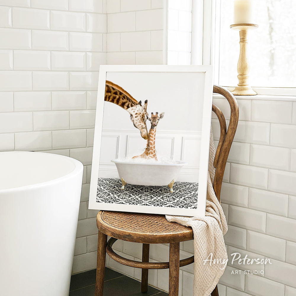 A framed photograph of two giraffes in a bathtub is displayed on a wooden chair in a bathroom setting.