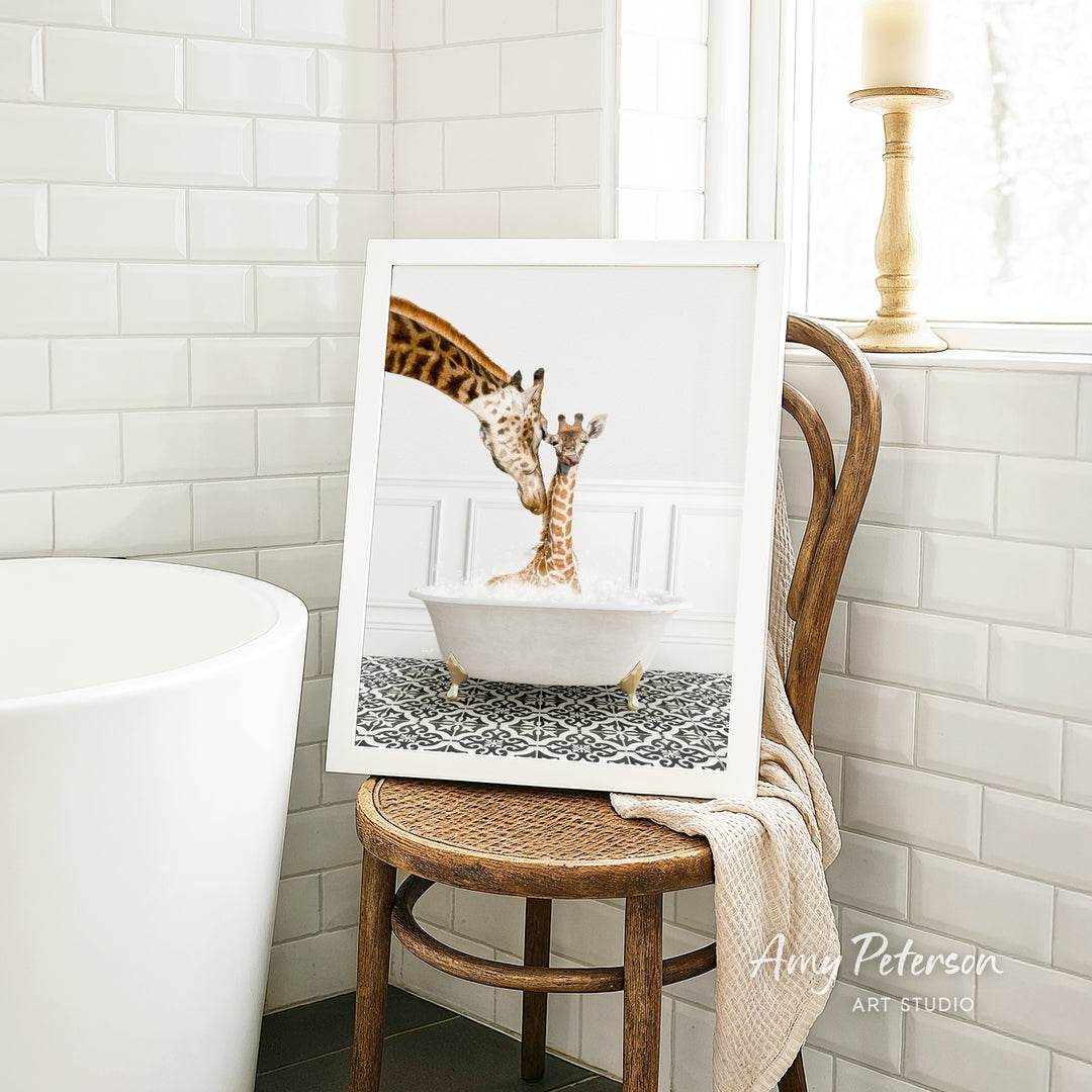 A framed photograph of two giraffes in a bathtub is displayed on a wooden chair in a bathroom setting.