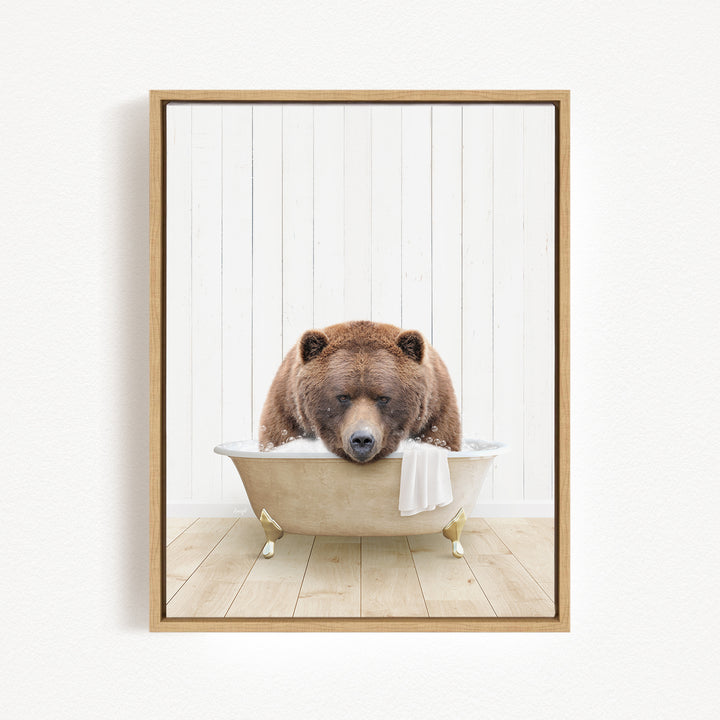 A brown bear is sitting in a bathtub filled with water, with a towel draped over the side of the tub.