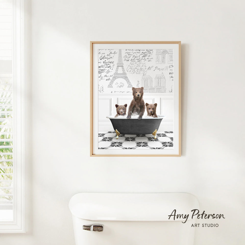 A framed print of three bears sitting in a bathtub, with a drawing of the Eiffel Tower in the background.