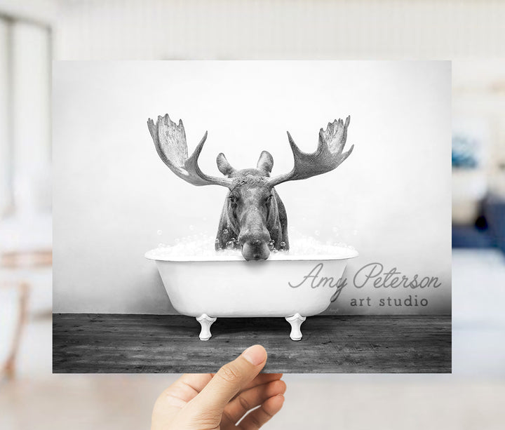 a person holding up a picture of a moose in a bathtub