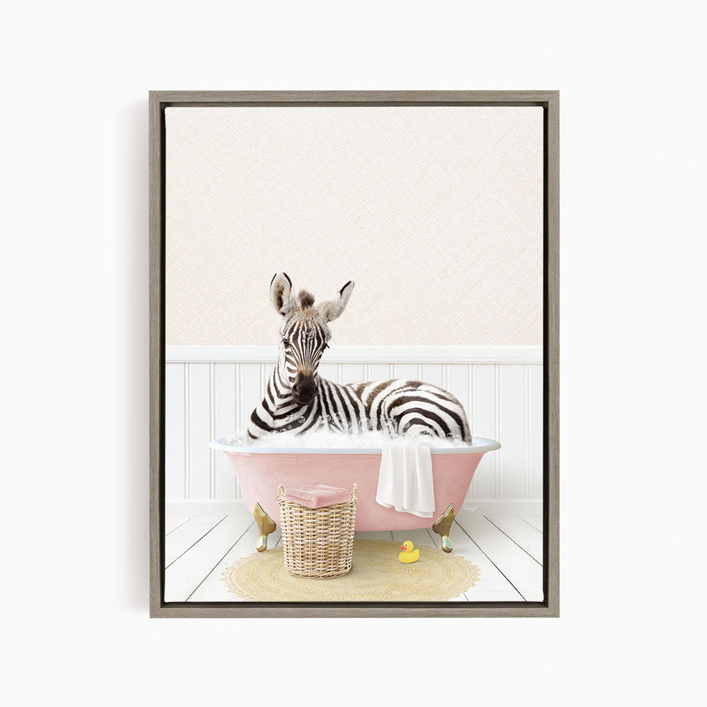 A zebra is sitting in a pink bathtub, surrounded by a basket of toys and a yellow rubber duck.