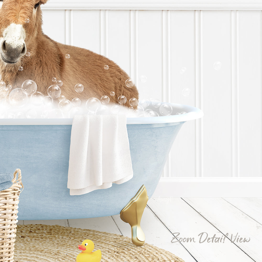 A donkey is sitting in a blue bathtub filled with bubbles, surrounded by a yellow rubber duck and a white towel.