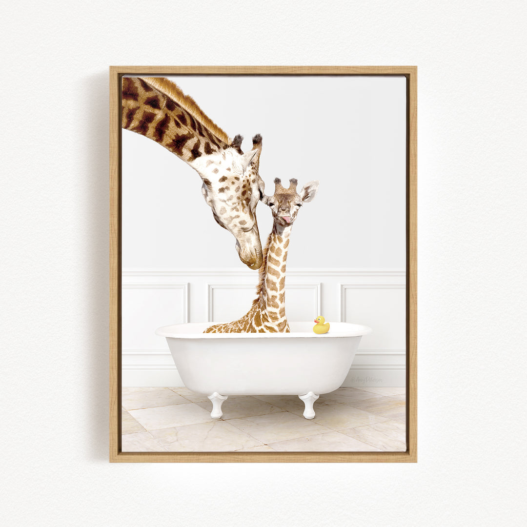 A mother giraffe and her baby giraffe are sitting together in a white bathtub, with a yellow rubber duck floating in the water.