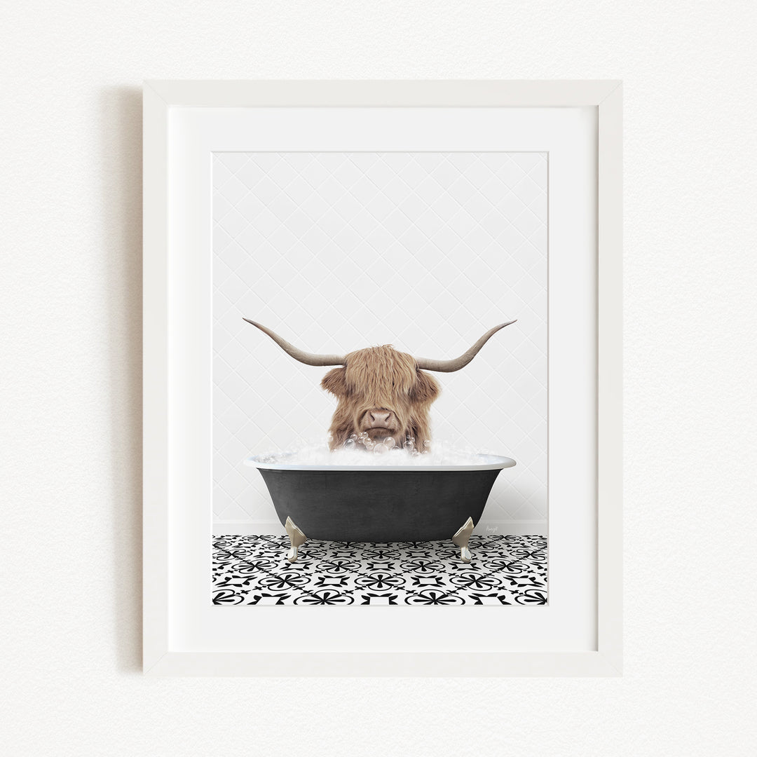 A framed image depicting a Highland cow with long horns sitting in a bathtub filled with water.