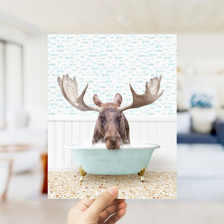 A moose with large antlers is sitting in a bathtub filled with water, surrounded by a pattern of fish.