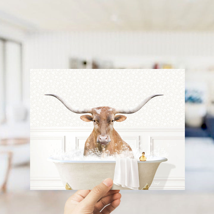 A hand holds up a collage of images featuring a horned animal, likely a cow or a bull, sitting in a bathtub filled with water and bubbles.