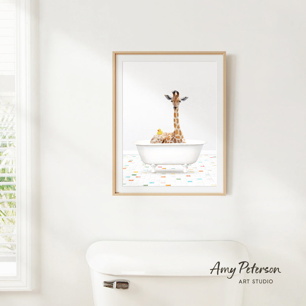 A framed image of a giraffe sitting in a white bathtub, surrounded by other animals, is hanging on a white wall.