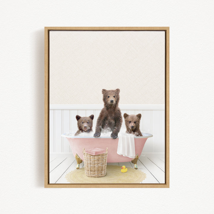 A framed image depicting three brown bears sitting in a pink bathtub, with a yellow rubber duck floating in the water.