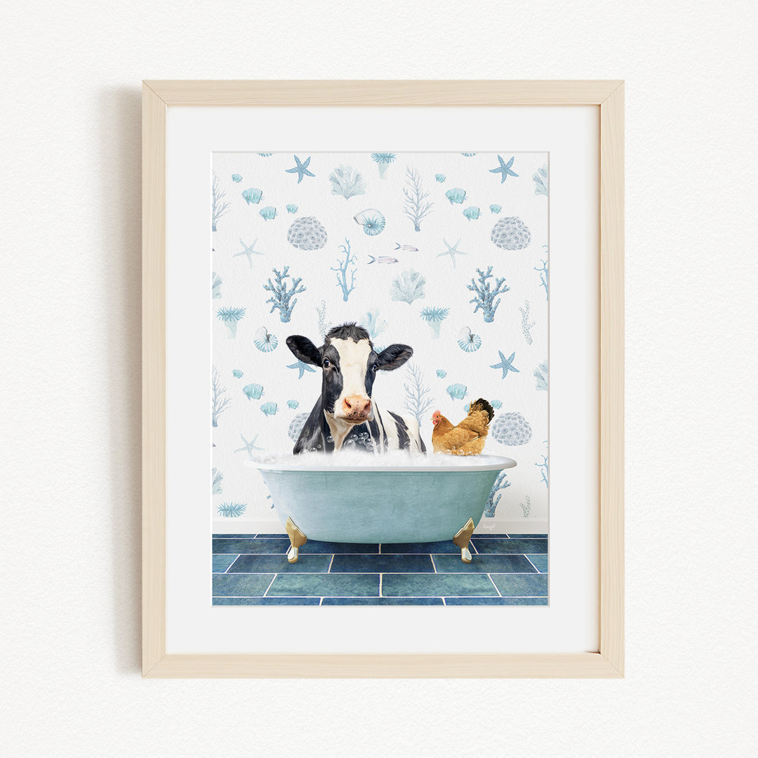 A framed image depicting a cow sitting in a bathtub, surrounded by a chicken and a bird, with a blue and white floral pattern on the wall behind them.