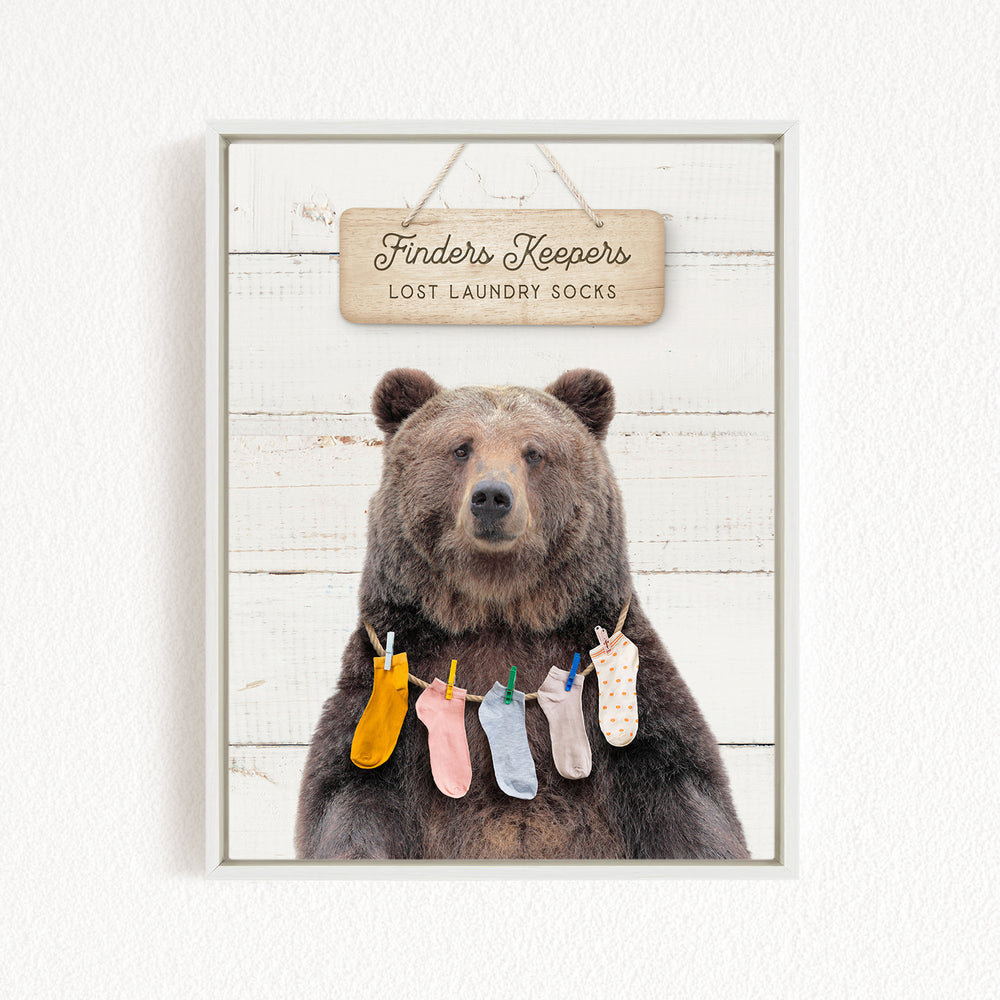 A wooden sign with the text "Finders Keepers Lost Laundry Socks" hangs above a bear wearing a variety of colorful socks.