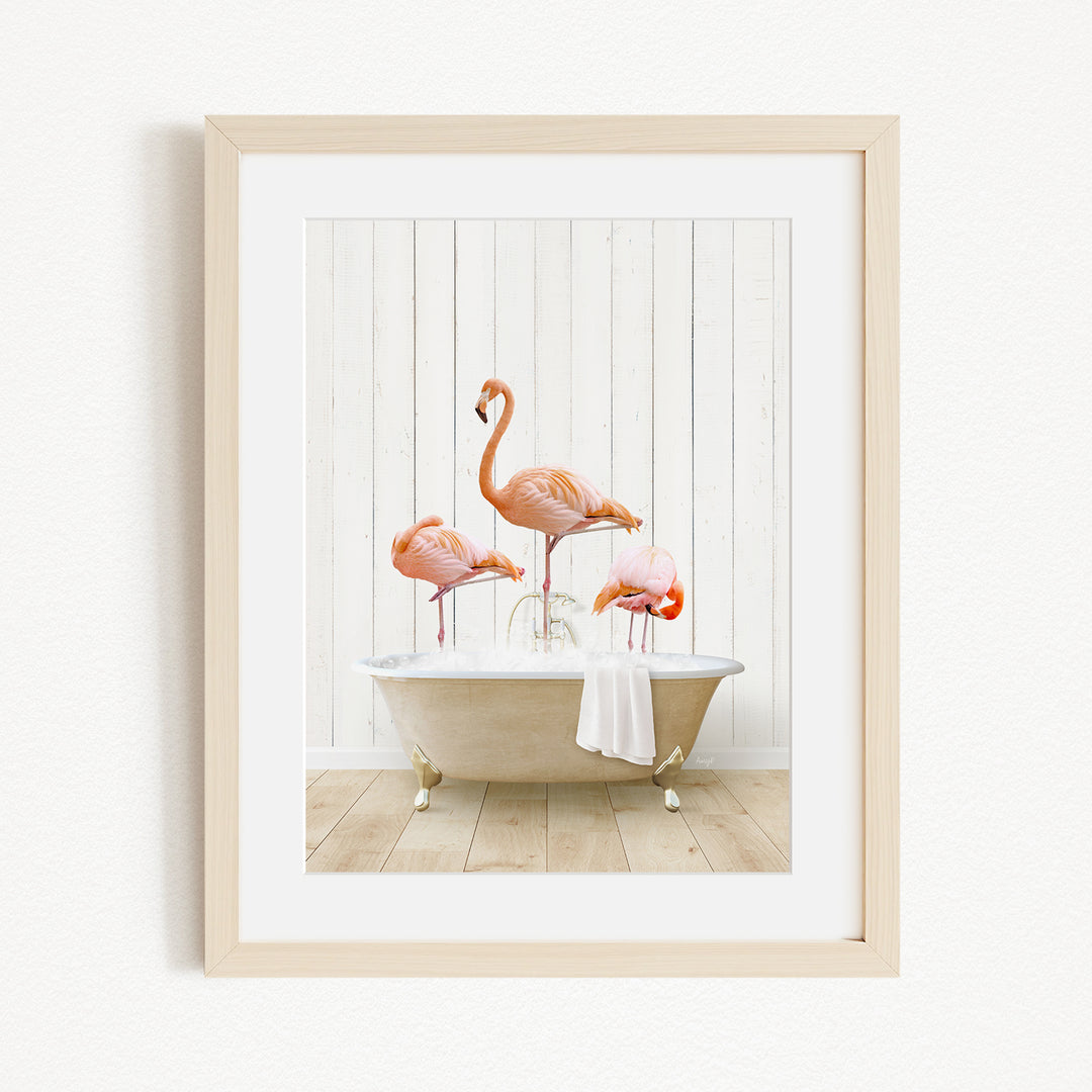 A framed image depicting three flamingos standing in a bathtub filled with water.