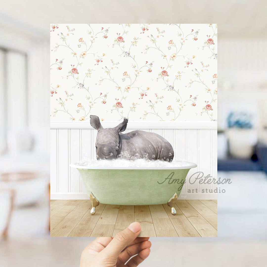 a hand holding up a photo of a rhino in a bathtub