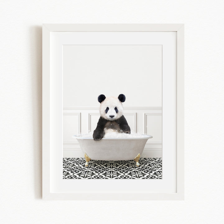 A panda bear sitting in a white bathtub filled with bubbles, surrounded by a black and white patterned rug.
