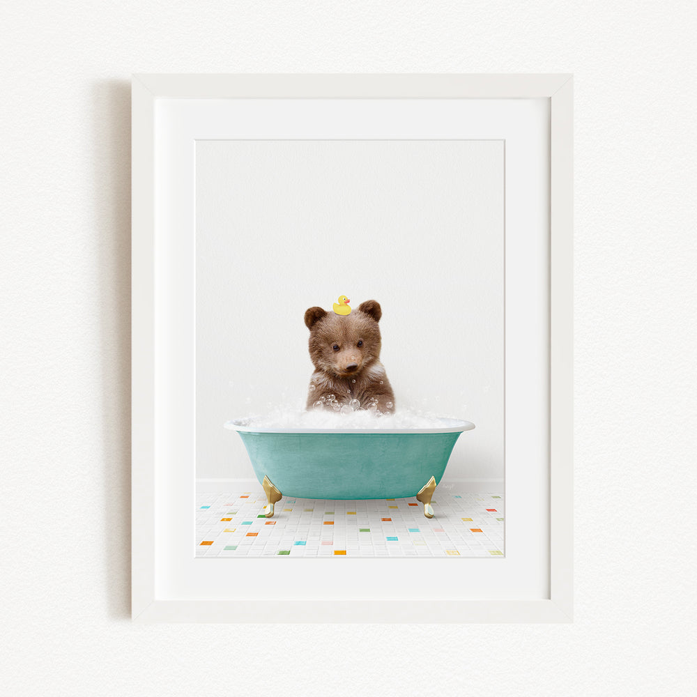 A brown bear sitting in a blue bathtub filled with bubbles, with a yellow rubber duck floating on the water.