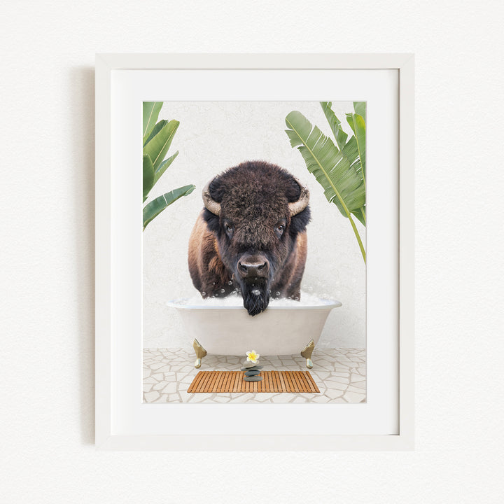 A buffalo is sitting in a bathtub filled with water, surrounded by tropical plants and a wooden mat on the floor.
