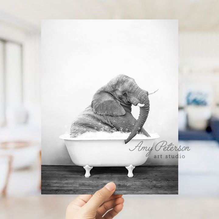 a hand holding up a black and white photo of an elephant in a bathtub