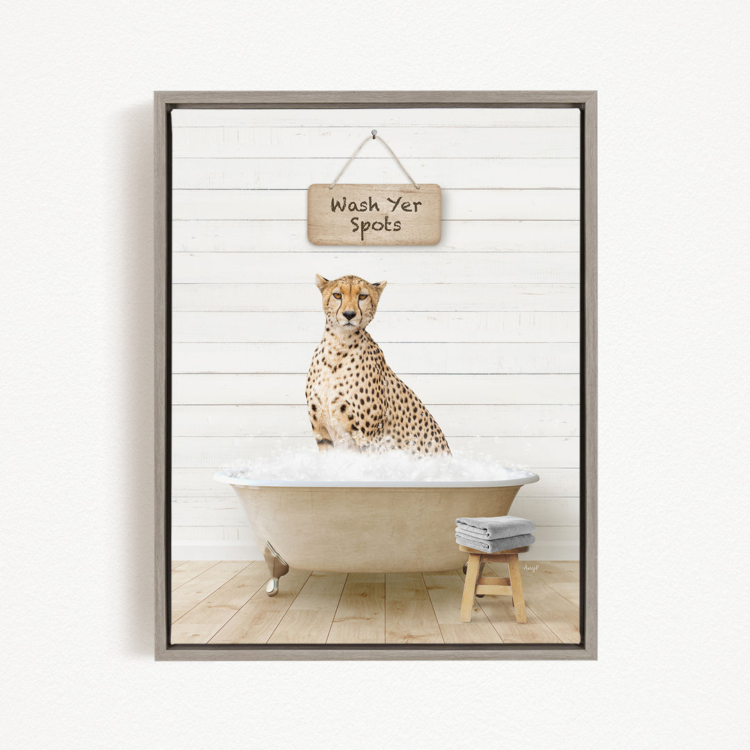 A cheetah sitting in a bathtub filled with water, with a sign above that says "Wash Yer Spots".