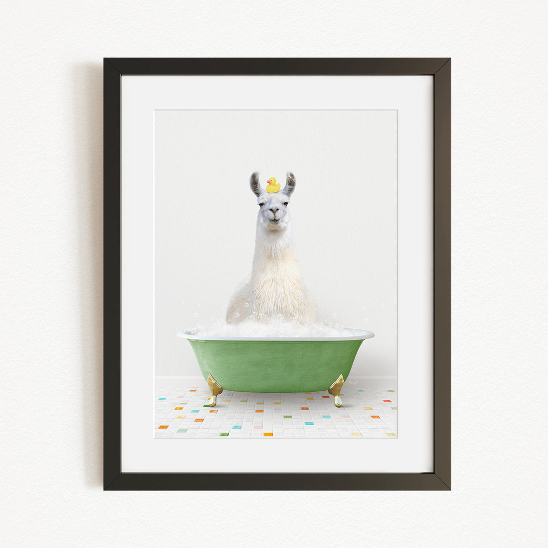 A white llama sitting in a green bathtub filled with bubbles, with a yellow rubber duck floating on the water.