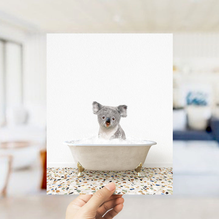 A koala sitting in a bathtub filled with water, looking at the camera.