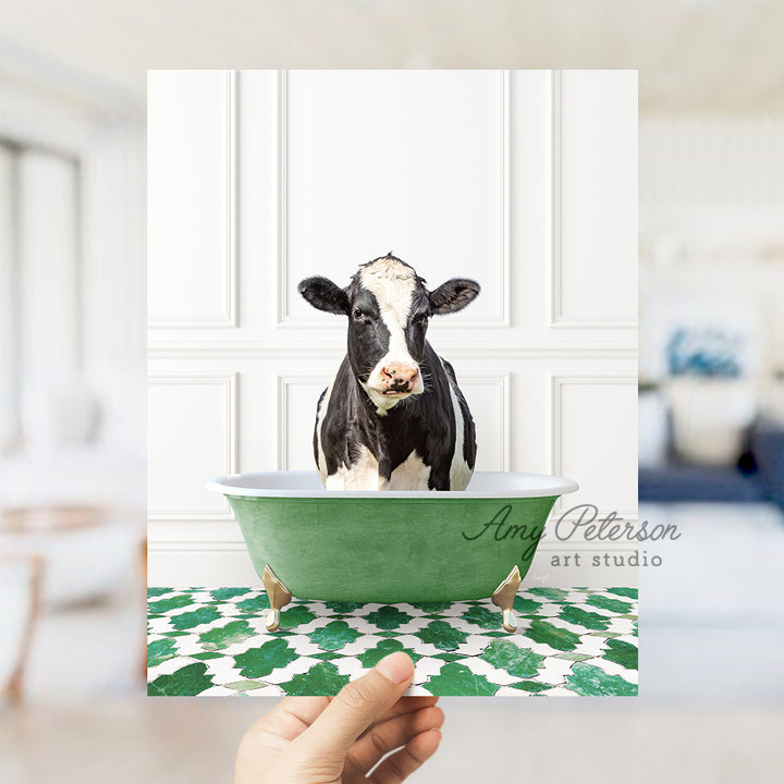 a hand holding a card with a picture of a cow in a bathtub