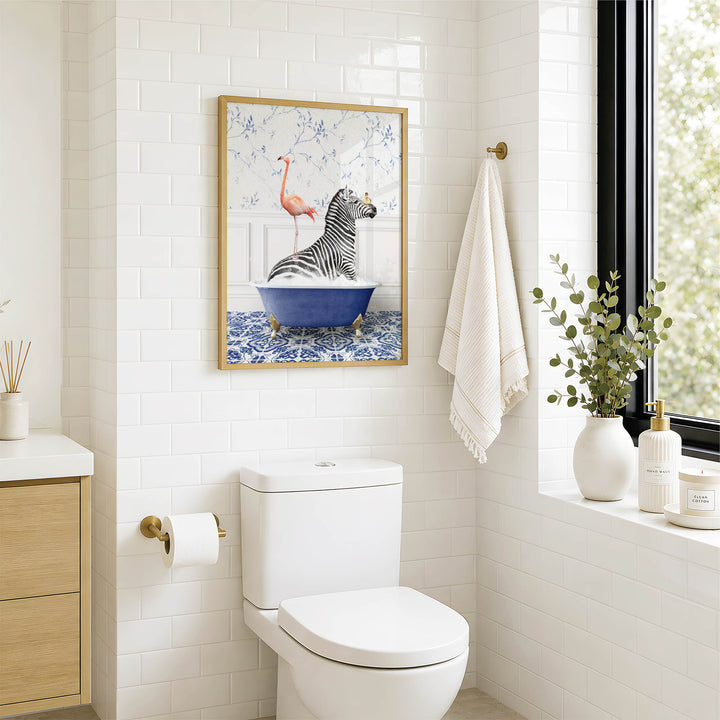 a bathroom with a white toilet, a framed picture of a zebra sitting in a bathtub, and a towel hanging on a rack.
