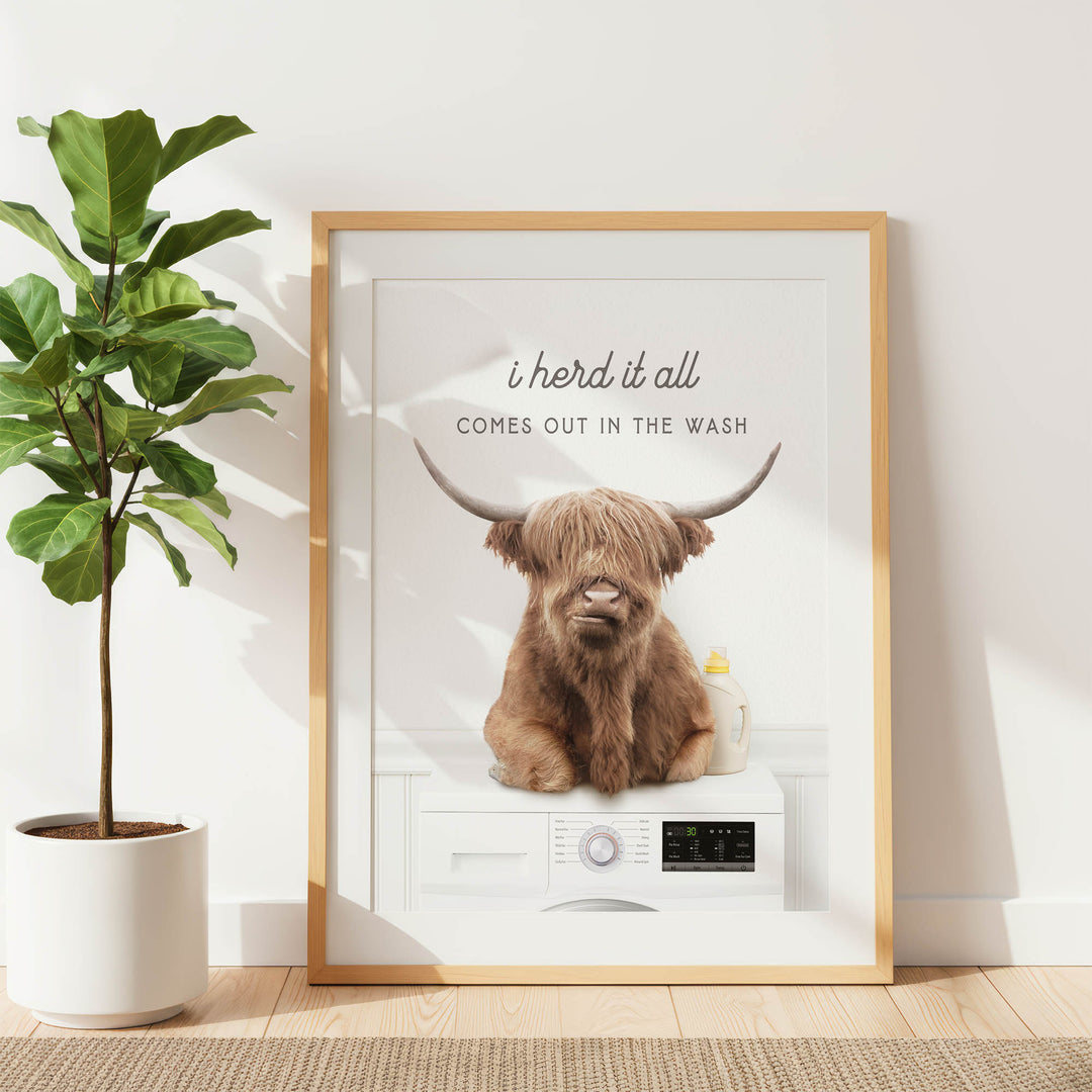 a framed poster with a cartoon image of a brown cow with horns sitting on a washing machine.