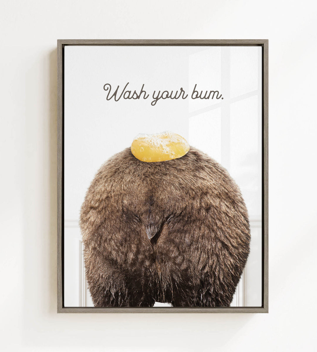 a close-up of a furry brown bear with a yellow object on its head, accompanied by the text "Wash your butt."