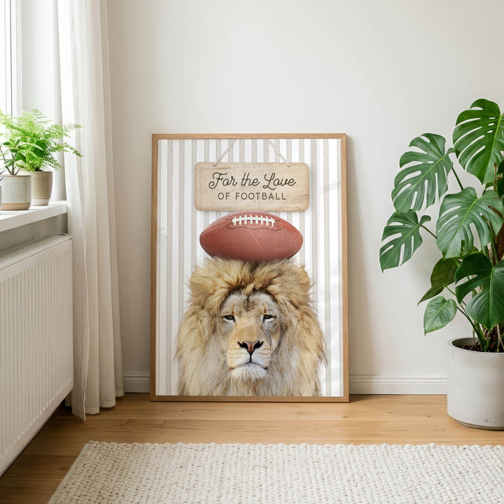 A framed poster featuring a lion's head with a football on its head, along with the text "For the Love of Football" is displayed on a wall in a room with a rug and potted plants.