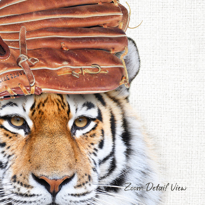 A close-up of a tiger's face with a baseball glove on its head.
